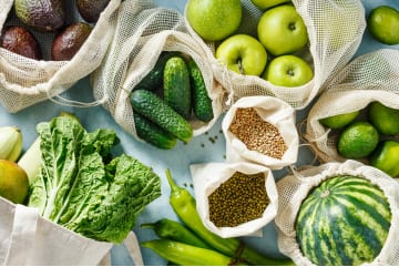Fresh vegetables, fruit and pulses arranged in open cloth produce bags