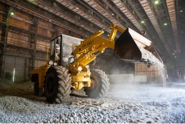 A wheel loader moving bulk material inside a covered storage warehouse